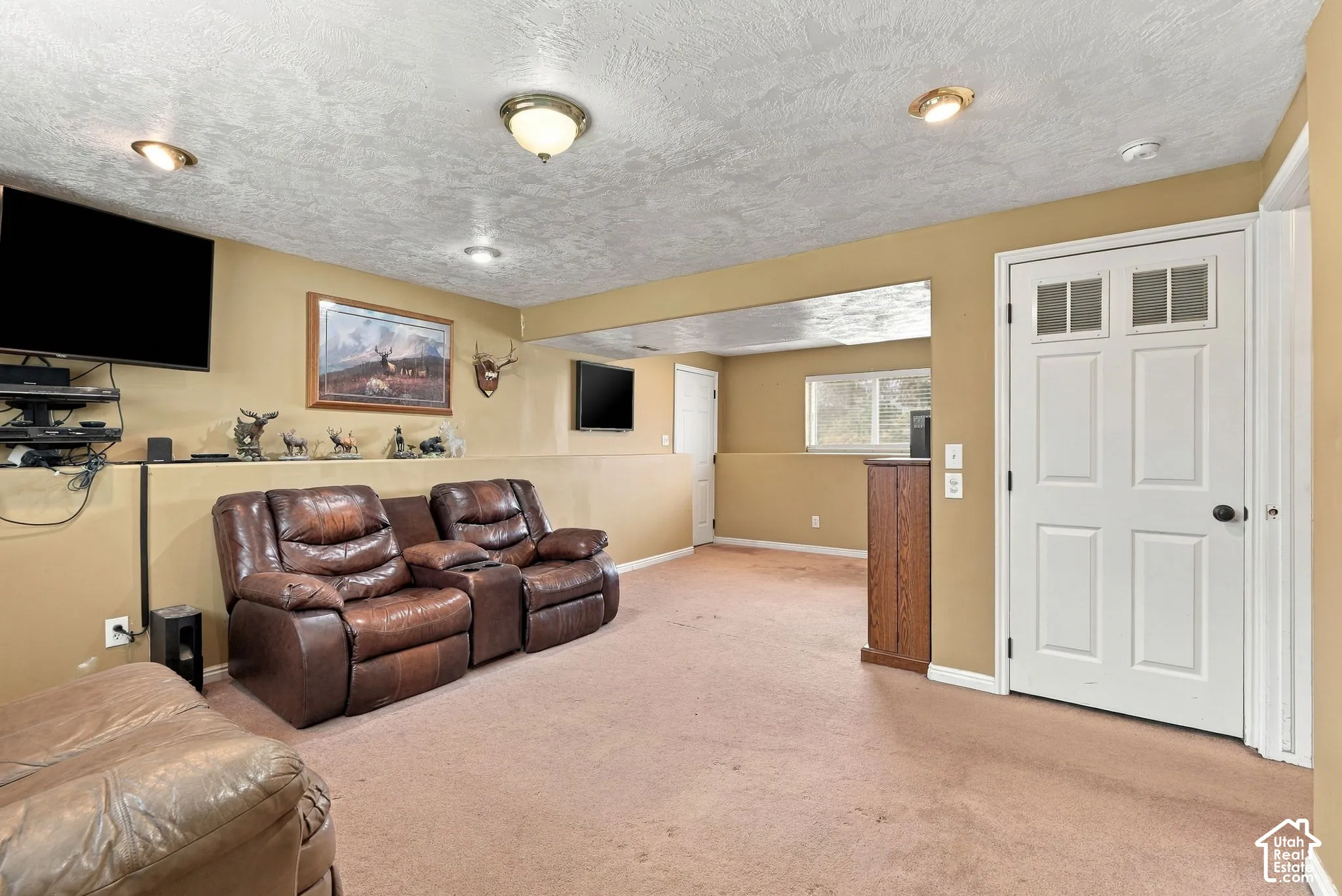 Spacious room featuring a textured ceiling, recessed lighting, wall-to-wall carpeting, and a white paneled door with glass inserts