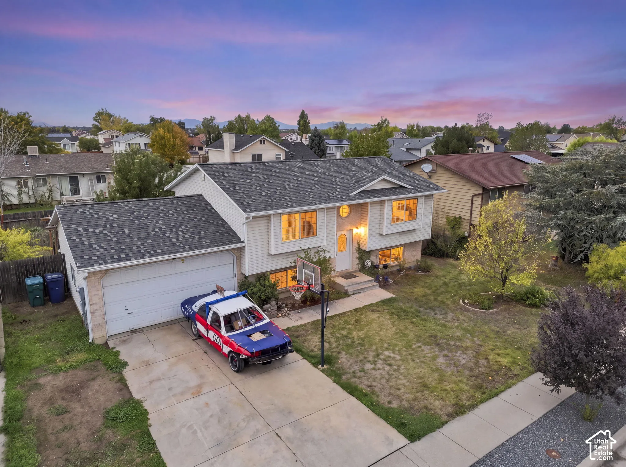 Split-level residence featuring horizontal vinyl siding, an attached two-car garage, and asphalt shingle roofing, set against a mountain backdrop
