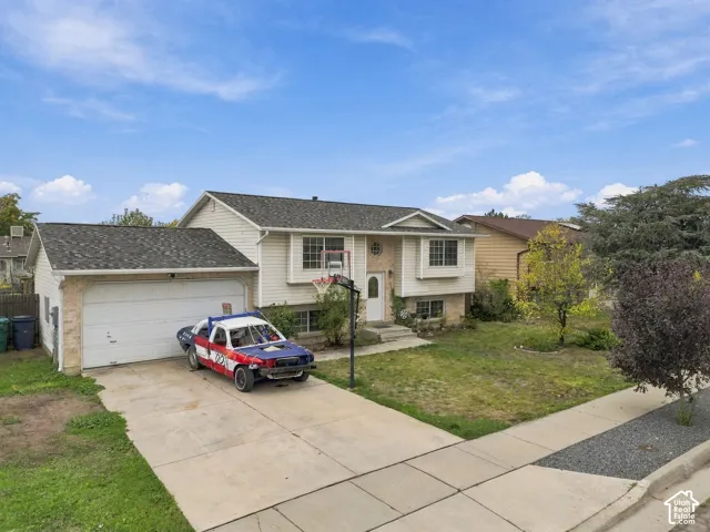 Split-level exterior featuring horizontal siding, stone veneer accents, a shingled roof, and an attached two-car garage