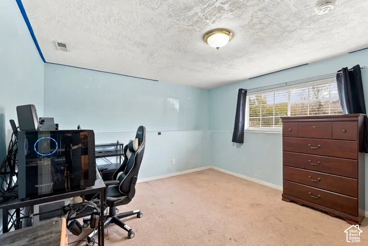 Carpeted room featuring a ceiling-mounted light fixture and a window with horizontal blinds