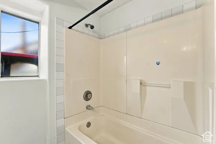 Bathtub with integrated surround, metal shower head, wall-mounted faucet, and window