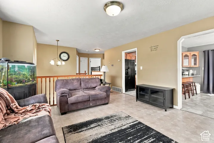 Living area featuring tile flooring, a multi-tier pendant light, and a wooden balustrade railing
