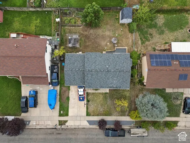 Aerial view of residential lot featuring a concrete driveway, grass yard area, and a wooden pergola