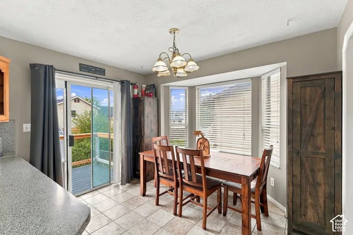 Dining area featuring ceramic tile flooring, a multi-light chandelier, a triple-pane bay window, and a sliding glass door providing exterior access
