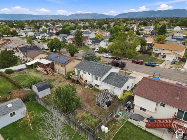 Aerial perspective of a property with an elevated wood deck, detached storage structure, and mountain backdrop