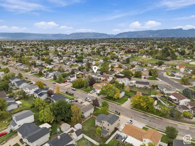 Aerial perspective of a residential property situated in a suburban setting with mountainous terrain on the horizon