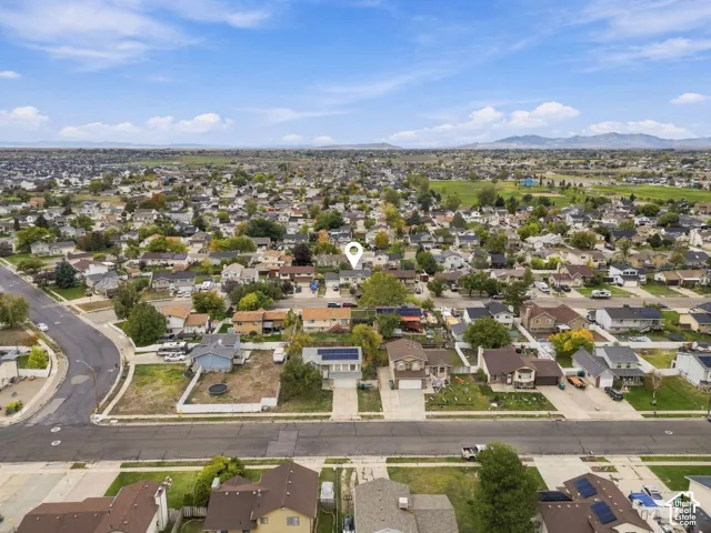 Aerial perspective featuring a residential property with roof-mounted solar panels, an attached two-car garage, and a concrete driveway