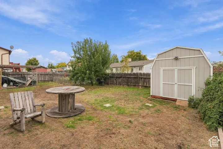 Backyard featuring a wood-panel storage shed, perimeter wood fencing, and mature trees