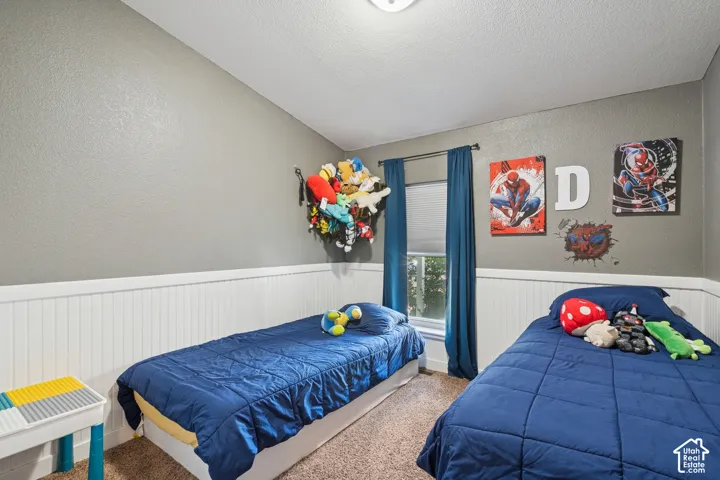 Interior room featuring white beadboard wainscoting, neutral wall paint, carpeted flooring, and a window with horizontal blinds