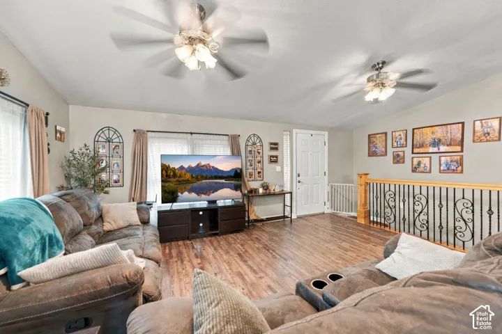 Wood-finish flooring, dual ceiling fans with light fixtures, and decorative wrought iron balustrade with wood railing