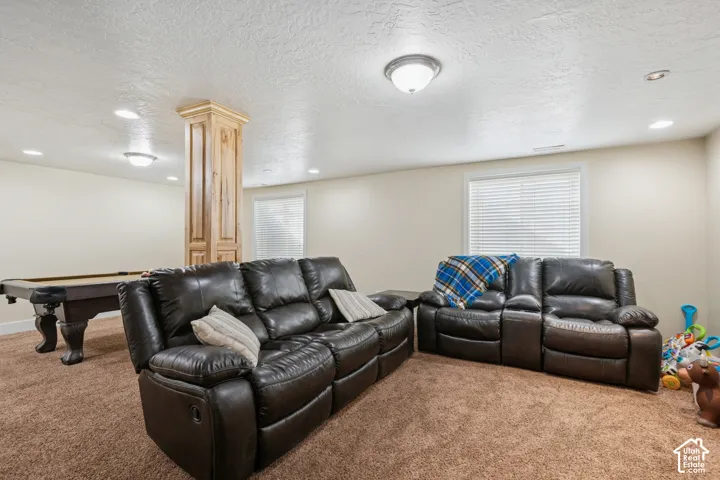 Spacious interior area featuring recessed lighting, a decorative wood-paneled support column, carpeting, and windows with integrated blinds