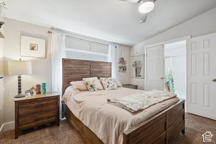 Bedroom featuring neutral wall paint, carpeted flooring, vaulted ceilings with a mounted light fixture, and double-panel doors