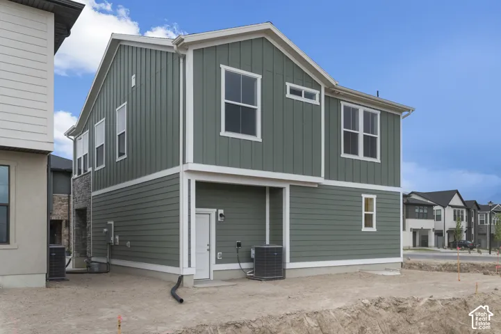 Two-story exterior featuring a mix of vertical board-and-batten and horizontal lap siding, stone masonry accents, a dedicated exterior door, and double-pane windows with white trim