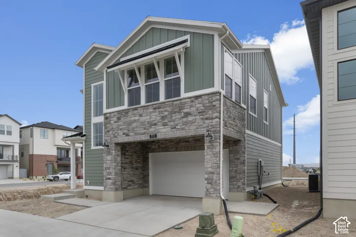 Two-story residence featuring vertical siding, stone veneer accents, multi-pane windows, and an integrated garage