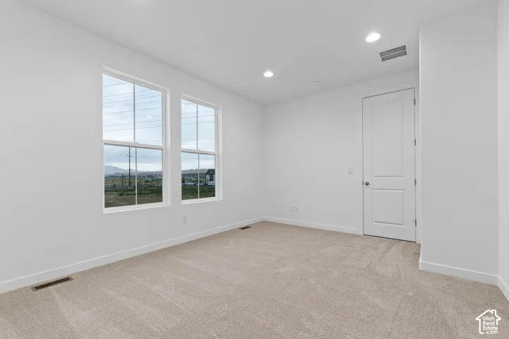 Neutral-toned carpeting, dual-pane windows with mountain scenery, recessed ceiling lighting, and a solid-core interior door