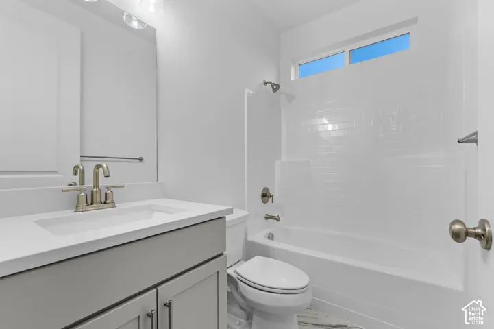 Bathroom featuring a light-toned vanity with an integrated rectangular sink, a white solid-surface countertop, subway-tile shower surround, and a transom window