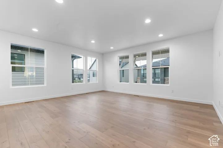 Neutral interior featuring light-toned wood-finish flooring, recessed lighting, and five double-pane windows