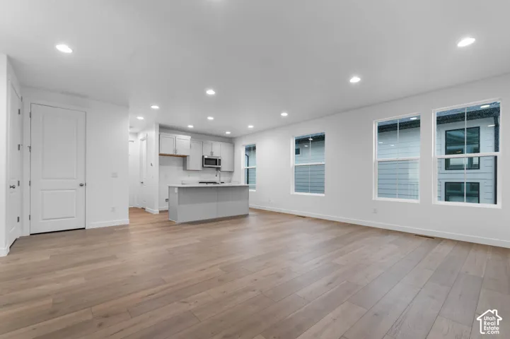 Open floor plan featuring wood-finish flooring, recessed lighting, expansive windows, a central island, and cabinetry