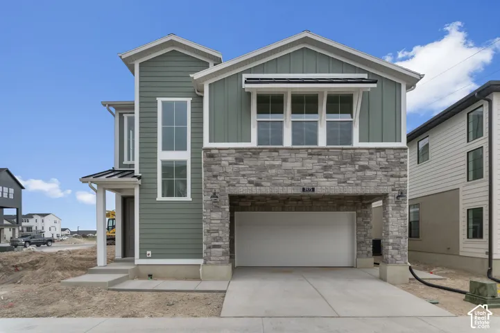 Exterior facade featuring green horizontal lap and vertical board-and-batten siding, stone veneer accents, multi-pane windows, and an attached two-car garage