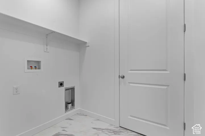 Laundry room featuring stone-patterned flooring, a solid-core paneled door, and built-in shelving