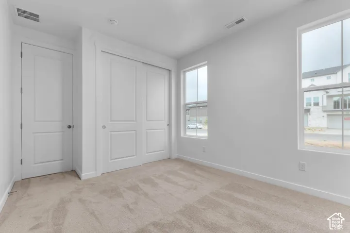 Neutral-toned wall-to-wall carpeting, dual-pane windows, and a sliding closet with multi-panel doors
