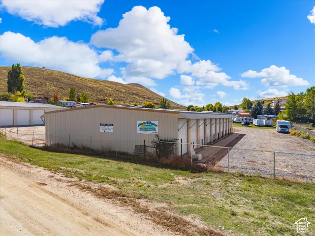 Commercial property featuring a metal building, multiple bay doors, paved drive, and a fenced perimeter