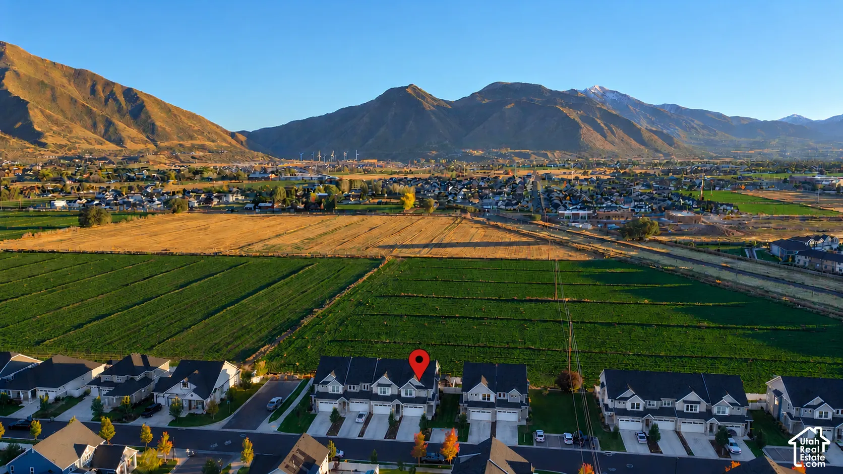 Multi-level residential property featuring a pitched roof, attached garage, and paved driveway, set against a prominent mountain backdrop