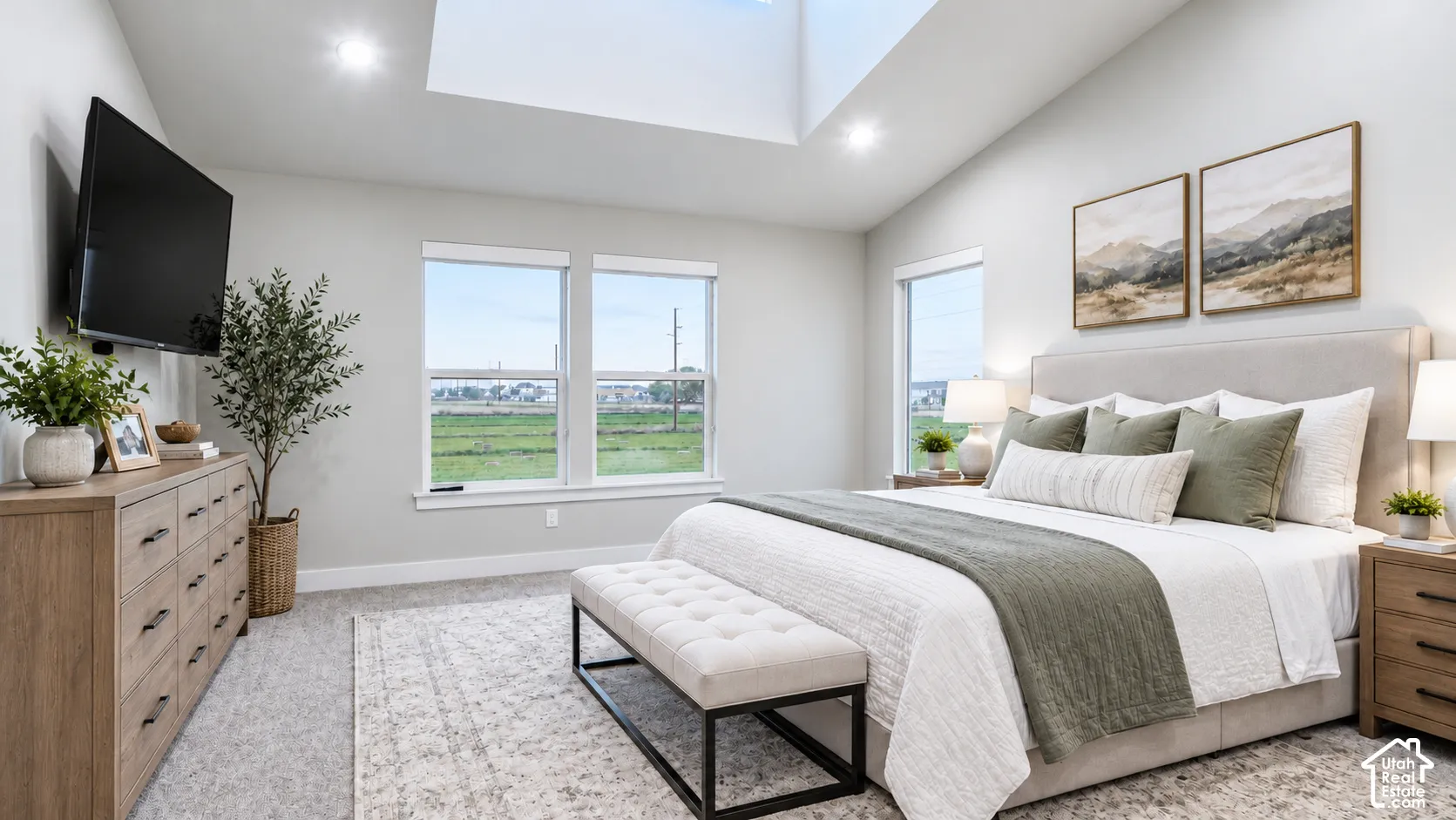 Vaulted ceilings featuring a large skylight, neutral wall tones, and expansive windows