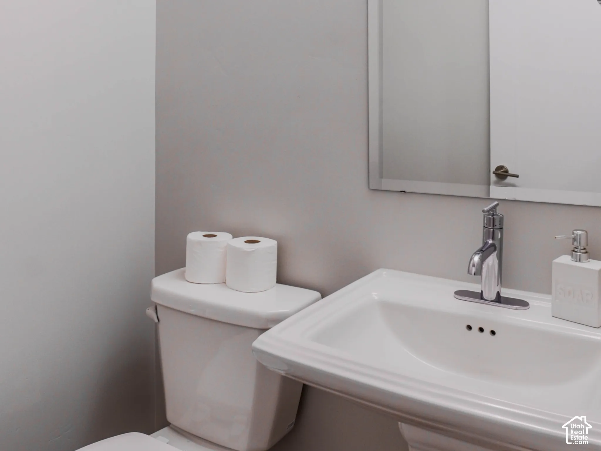 Pedestal sink with a single-handle faucet, wall-mounted mirror, and three-light fixture