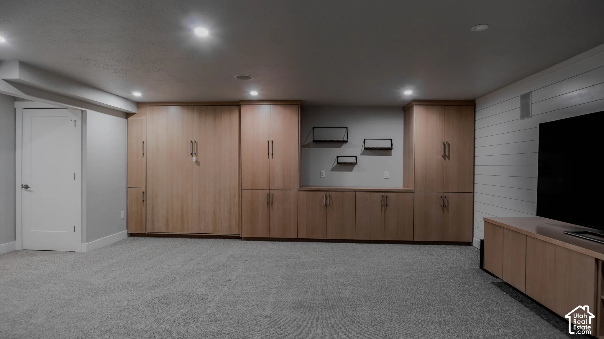 Custom floor-to-ceiling cabinetry, shiplap wall accent, recessed lighting, and wall-to-wall carpeting
