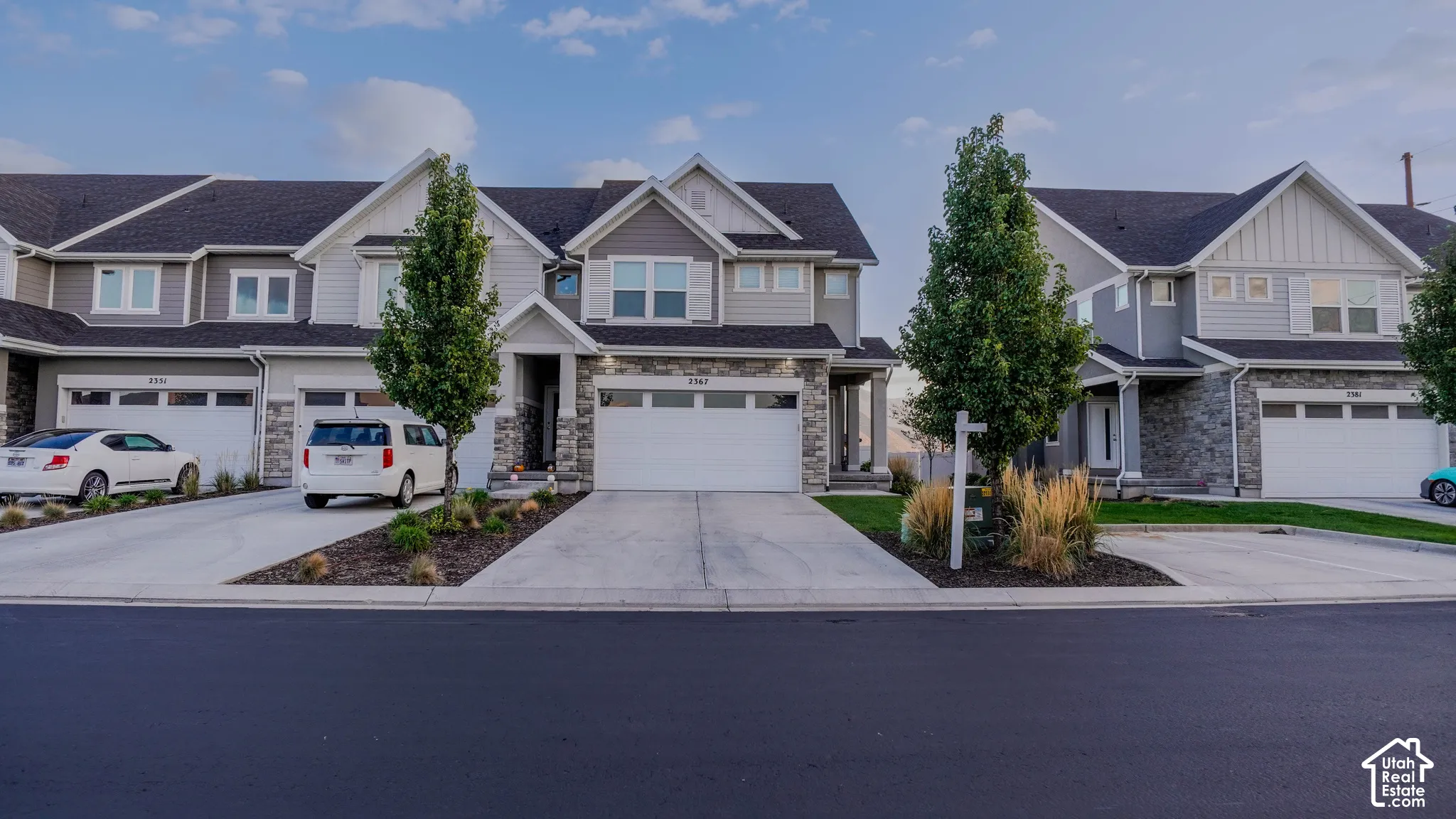 Multi-level exterior featuring stone veneer accents, lap siding, a pitched roofline, and attached two-car garages
