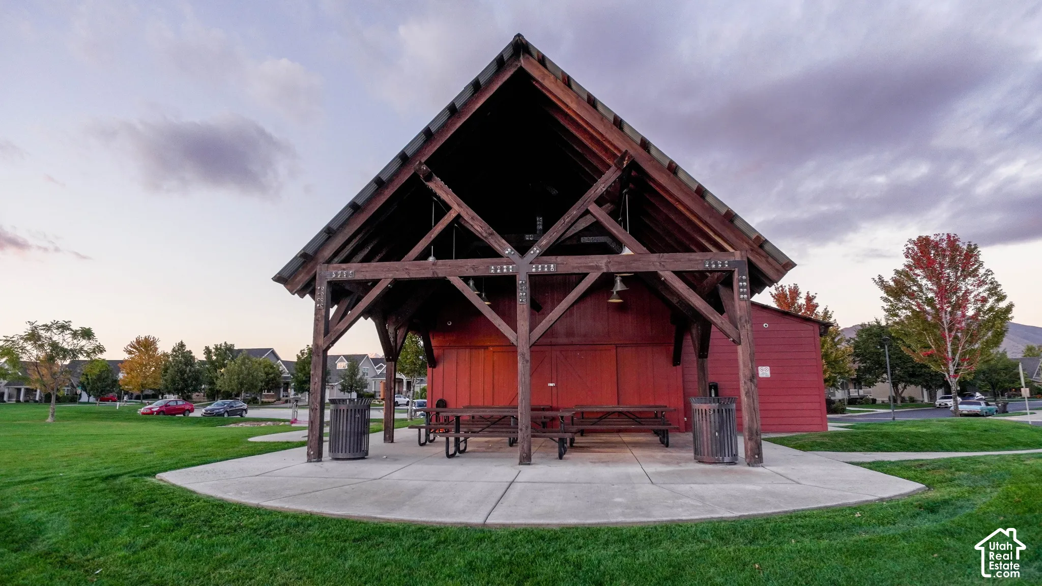 Open-air pavilion featuring exposed timber-frame construction, a high-pitched roof, and a concrete foundation