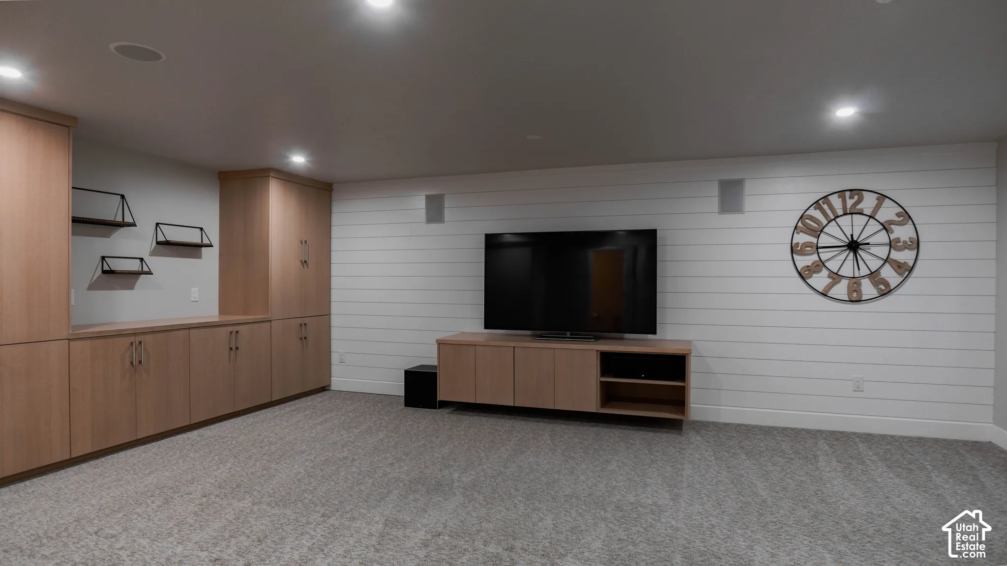 Built-in wood-finish cabinetry, horizontal shiplap wall detailing, integrated wall-mounted speakers, and recessed ceiling lighting