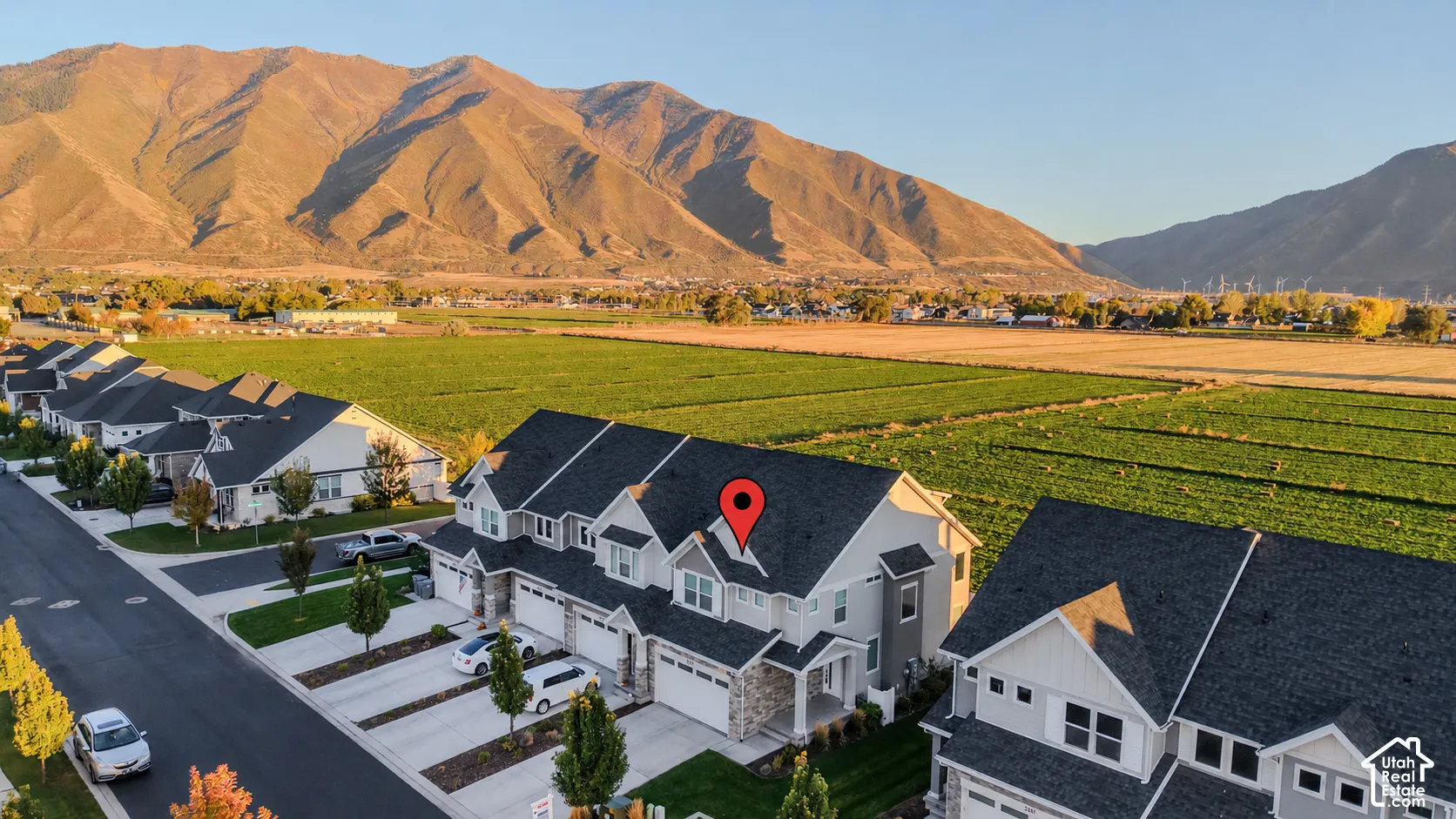 Multi-level residence featuring a composite shingle roof, stone veneer exterior, attached two-car garage, and mountainous backdrop