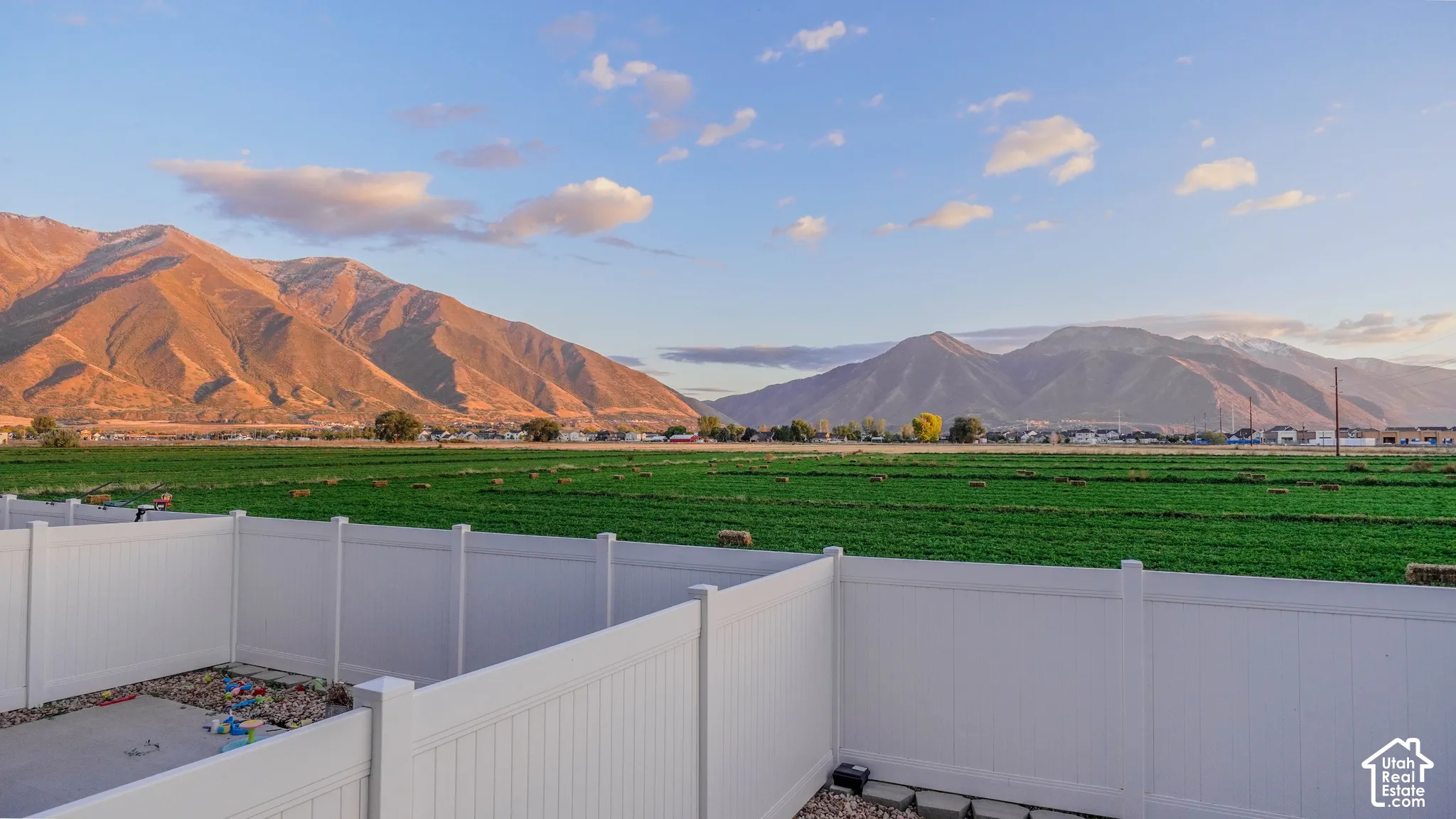 White vinyl privacy fencing enclosing a concrete patio with mountain and agricultural scenery