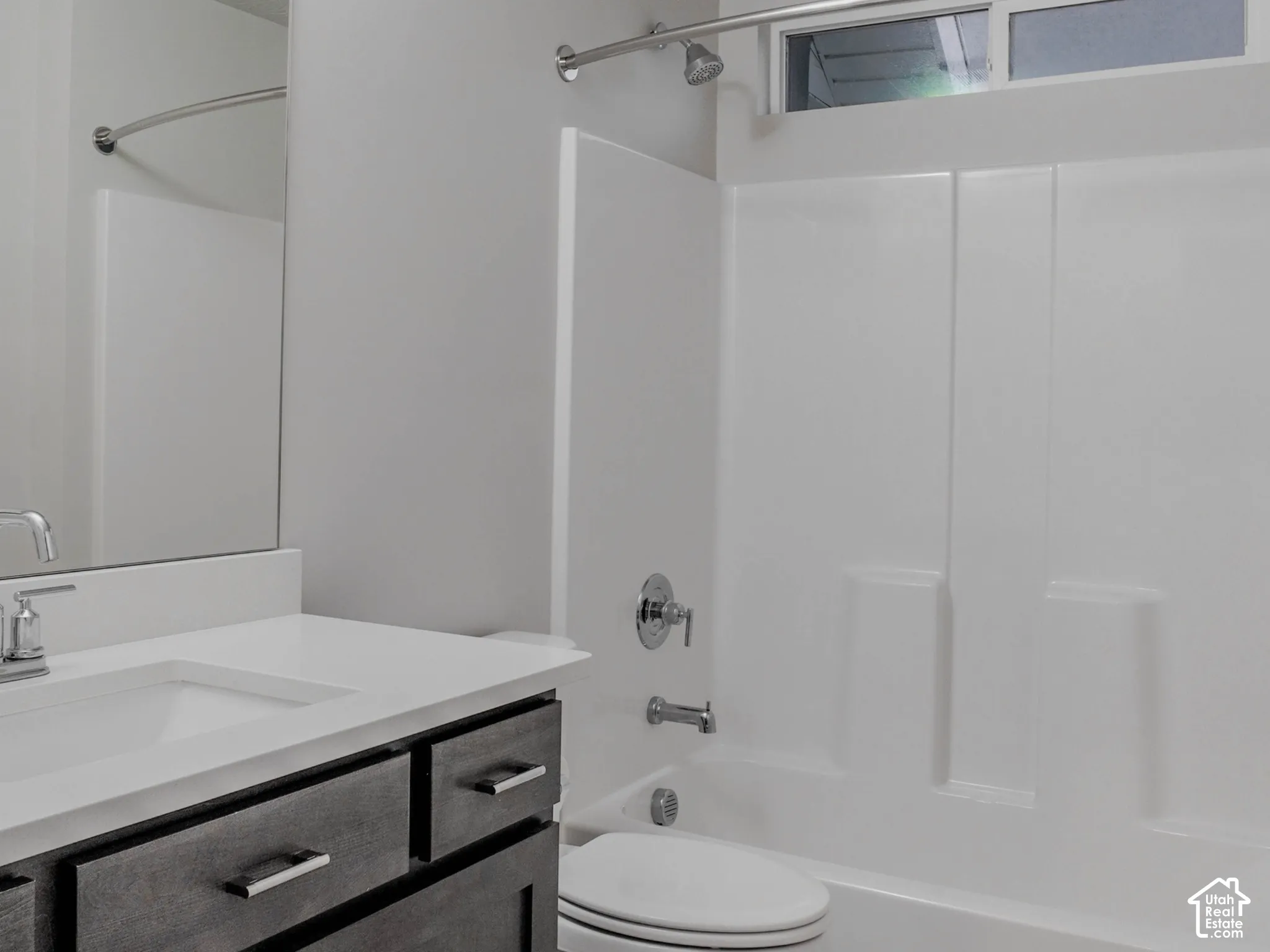 Bathroom featuring a dark wood-finish vanity with a quartz countertop, patterned tile flooring, a large wall-mounted mirror, and a tub-shower combination with a transom window