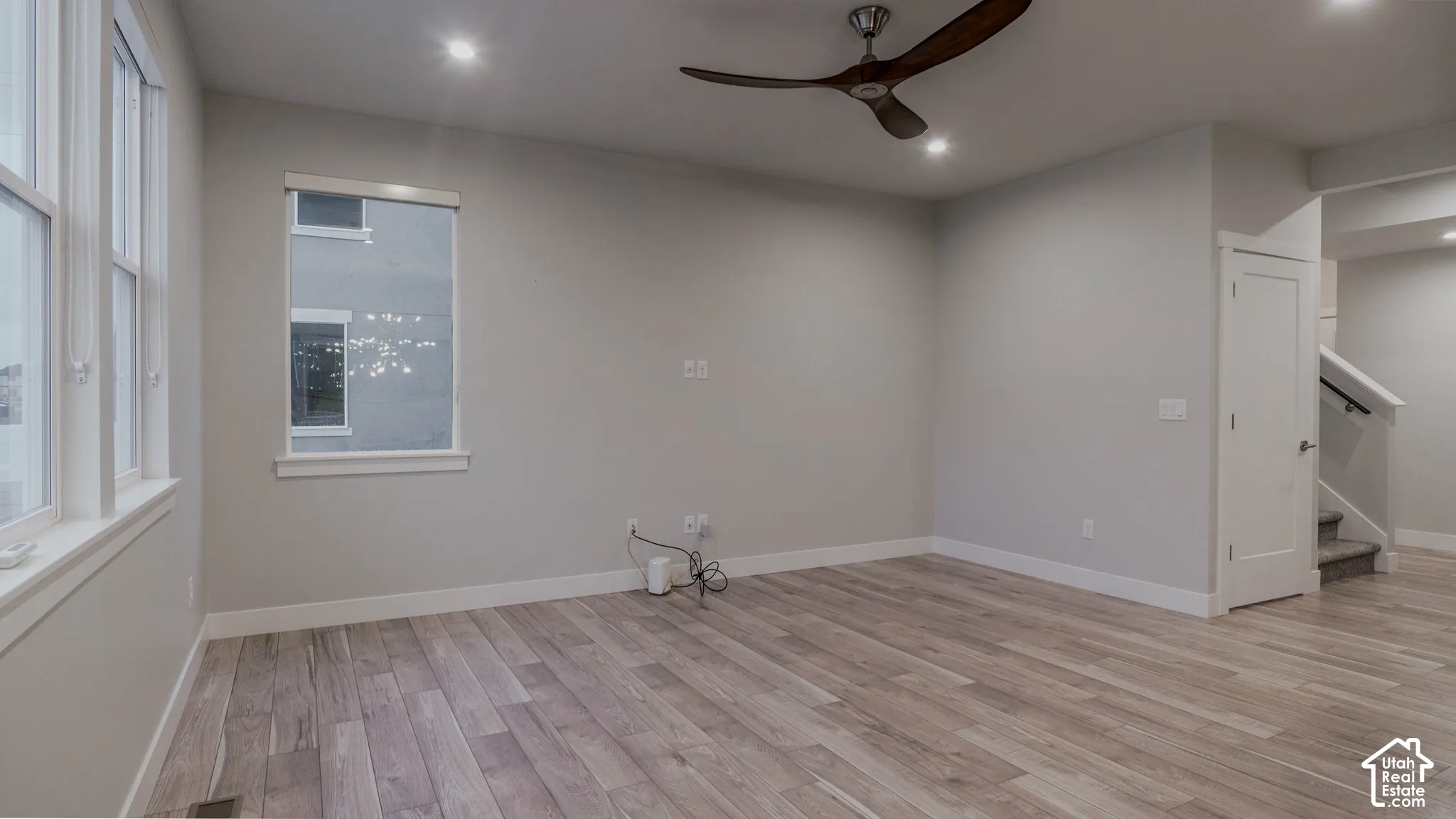 Room featuring LVP flooring, recessed lighting, a modern ceiling fan with curved blades, and multiple windows