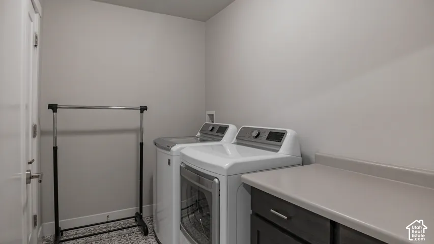 Dedicated laundry space featuring countertops, dark-toned cabinetry, and patterned tile flooring
