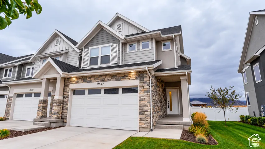 Multi-level exterior featuring a stone veneer facade, horizontal and vertical lap siding, gable roofline, multi-pane garage door, and covered entryway