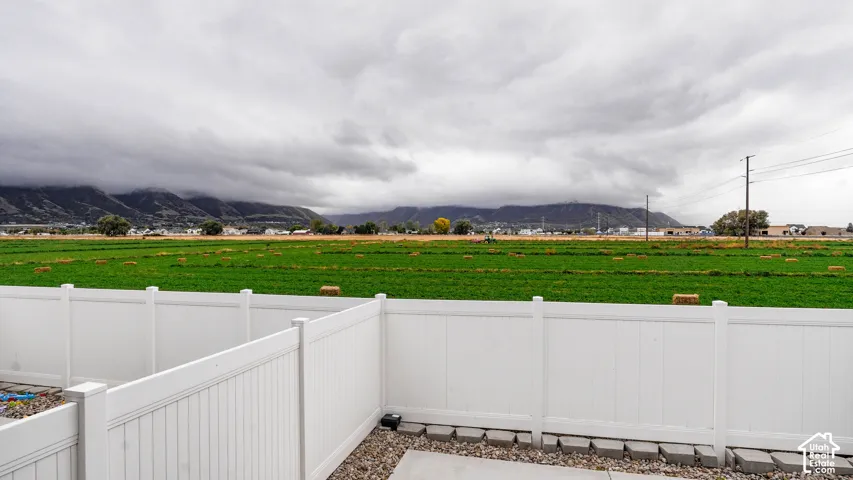 White vinyl perimeter fencing, stone-lined concrete patio, and prominent mountain backdrop