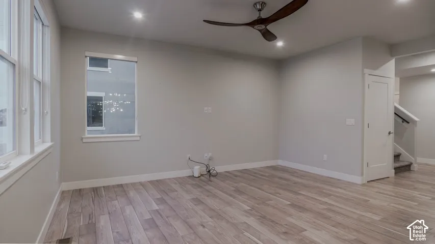 Room featuring LVP flooring, recessed lighting, a modern ceiling fan with curved blades, and multiple windows