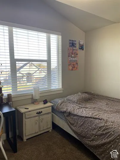 Vaulted ceiling, neutral wall tones, and a large window featuring horizontal blinds
