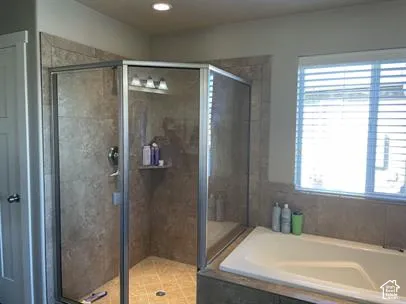 Corner walk-in shower with tile surround and glass enclosure, integrated soaking tub with matching tile deck, and recessed lighting