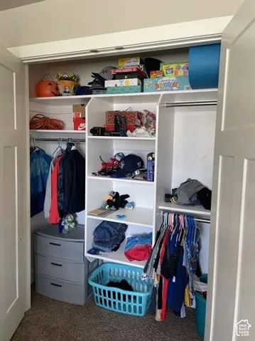 Closet featuring white built-in shelving, dual metal clothing rods, and double-panel doors