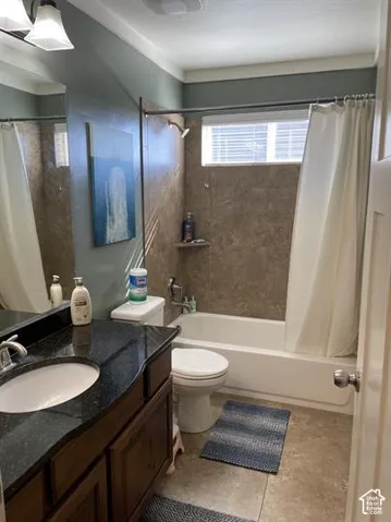 Dark stone vanity countertop with an integrated undermount sink, dark wood-finish cabinetry, shower-tub combination featuring tile surround, and horizontal window