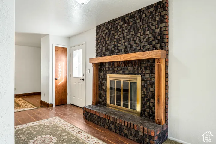 Floor-to-ceiling dark brick fireplace featuring a wood mantel, raised hearth, and brass-finish glass enclosure