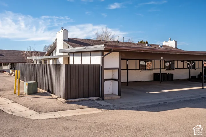 Exterior featuring white painted brick masonry, dark-toned trim, two masonry chimneys, and a covered carport