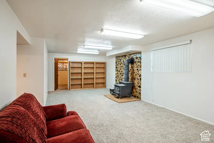 Interior space featuring built-in wood shelving, a cast-iron wood stove, and a stone-accented hearth