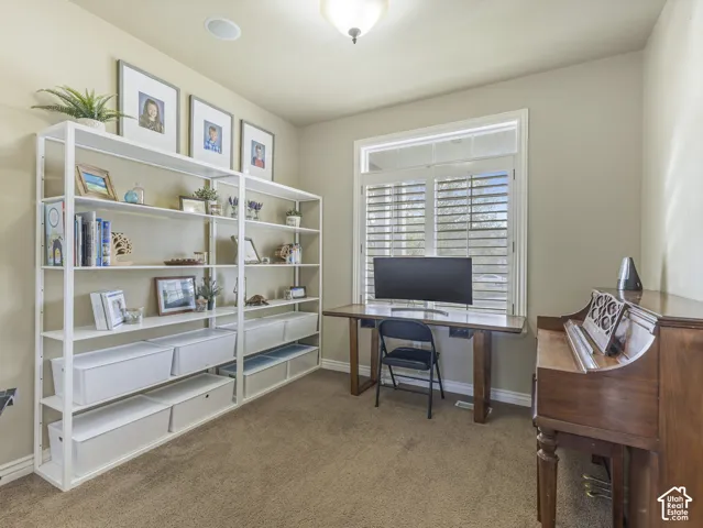 Neutral-toned room featuring a window with integrated white shutters, carpeted flooring, and a flush-mount light fixture