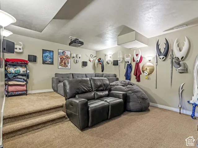 Multi-level room featuring wall-to-wall carpeting, elevated platform area, ceiling-mounted projection equipment, and multiple wall-mounted sconce light fixtures